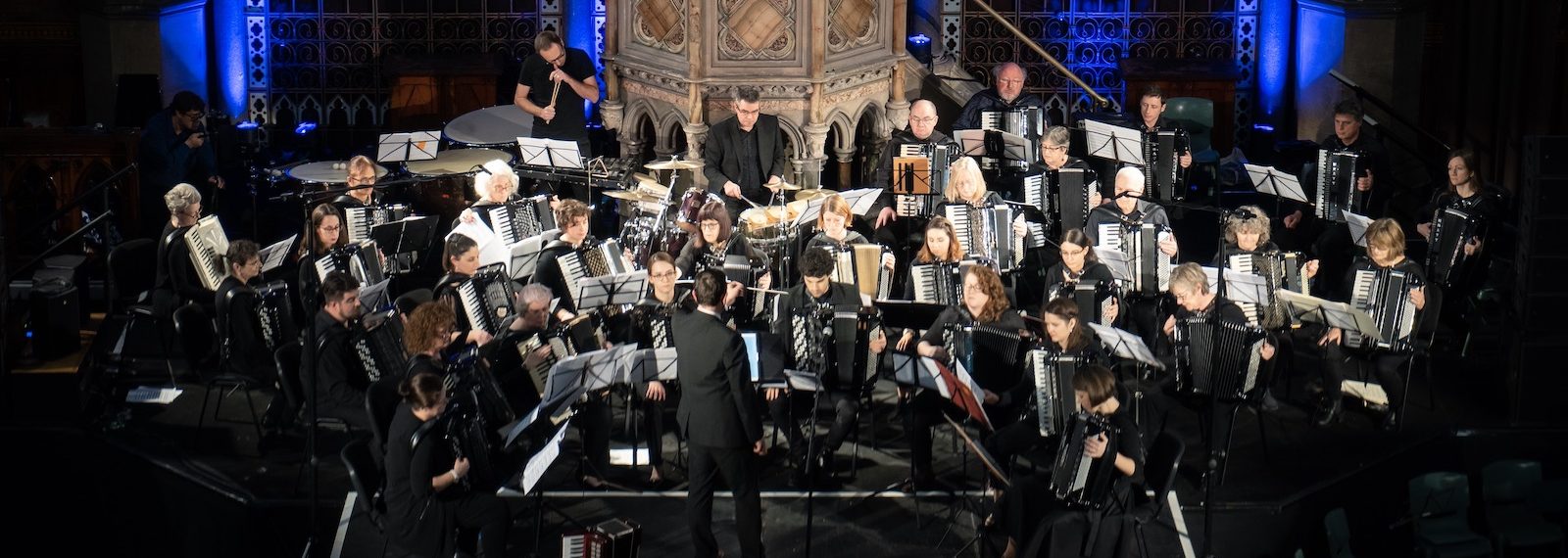 London Accordion Orchestra in concert at Union Chapel in front of blue lights